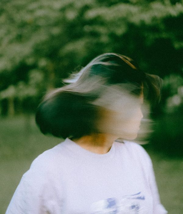 Woman performing a gentle, flowing movement in a calm setting.